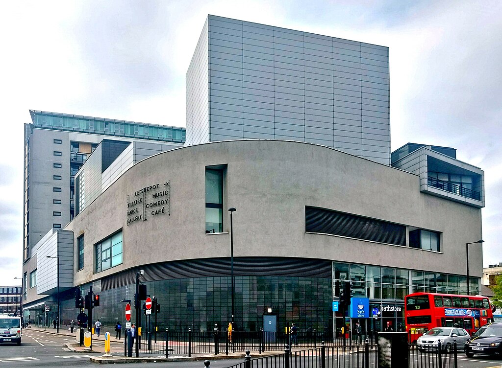 A modern building with huge curved glass windows, with a large main entrance way | Philafrenzy, CC BY-SA 4.0