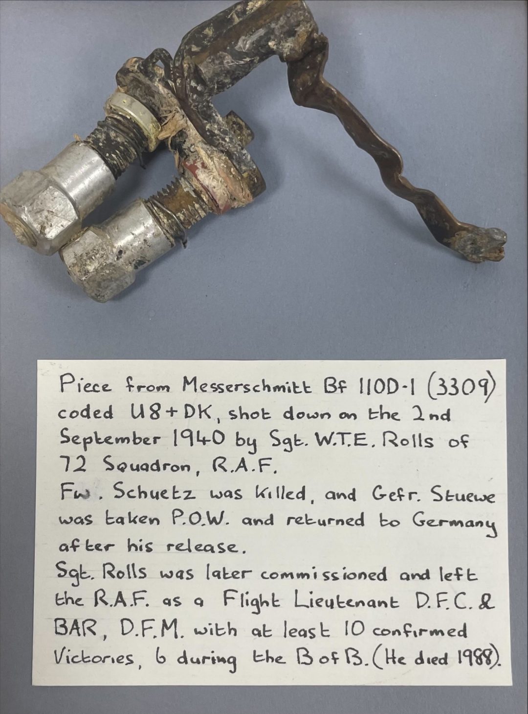 Rusted aircraft part with an informational note about its WWII history and Sgt. W.T.E. Rolls's service.