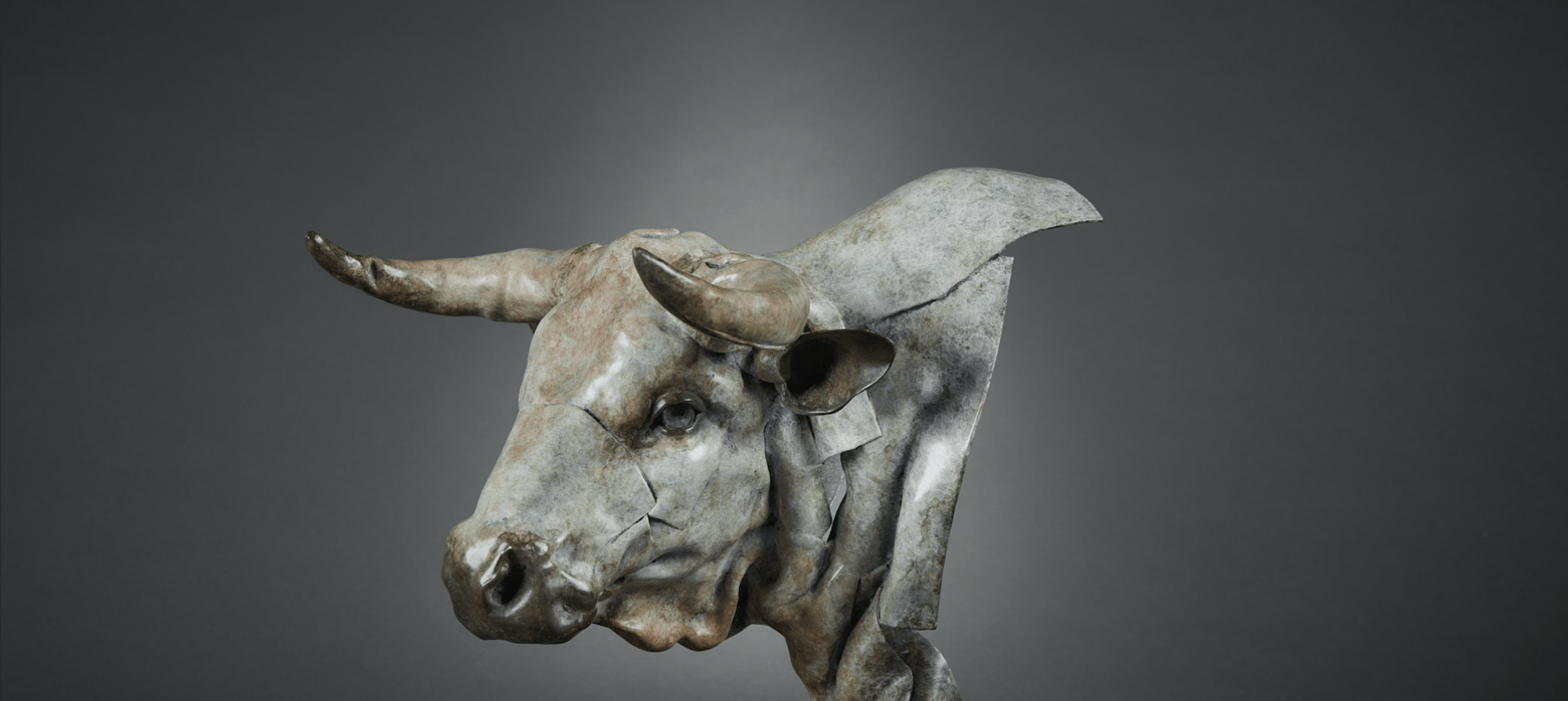 Metal bull sculpture with detailed head and horns against a dark background.