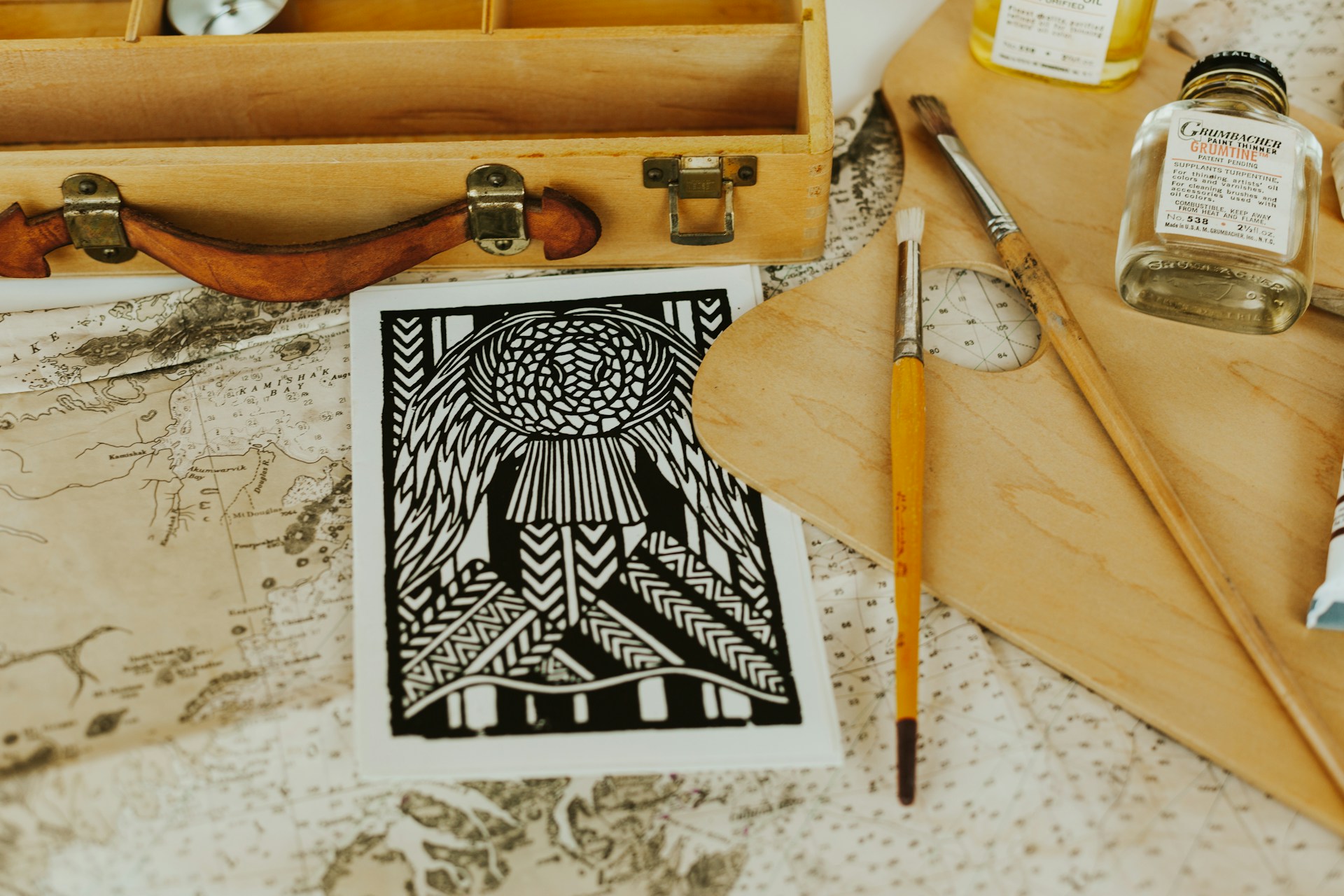 Black and white mandala artwork surrounded by painting supplies and maps. | Photo by Alina Belous on Unsplash