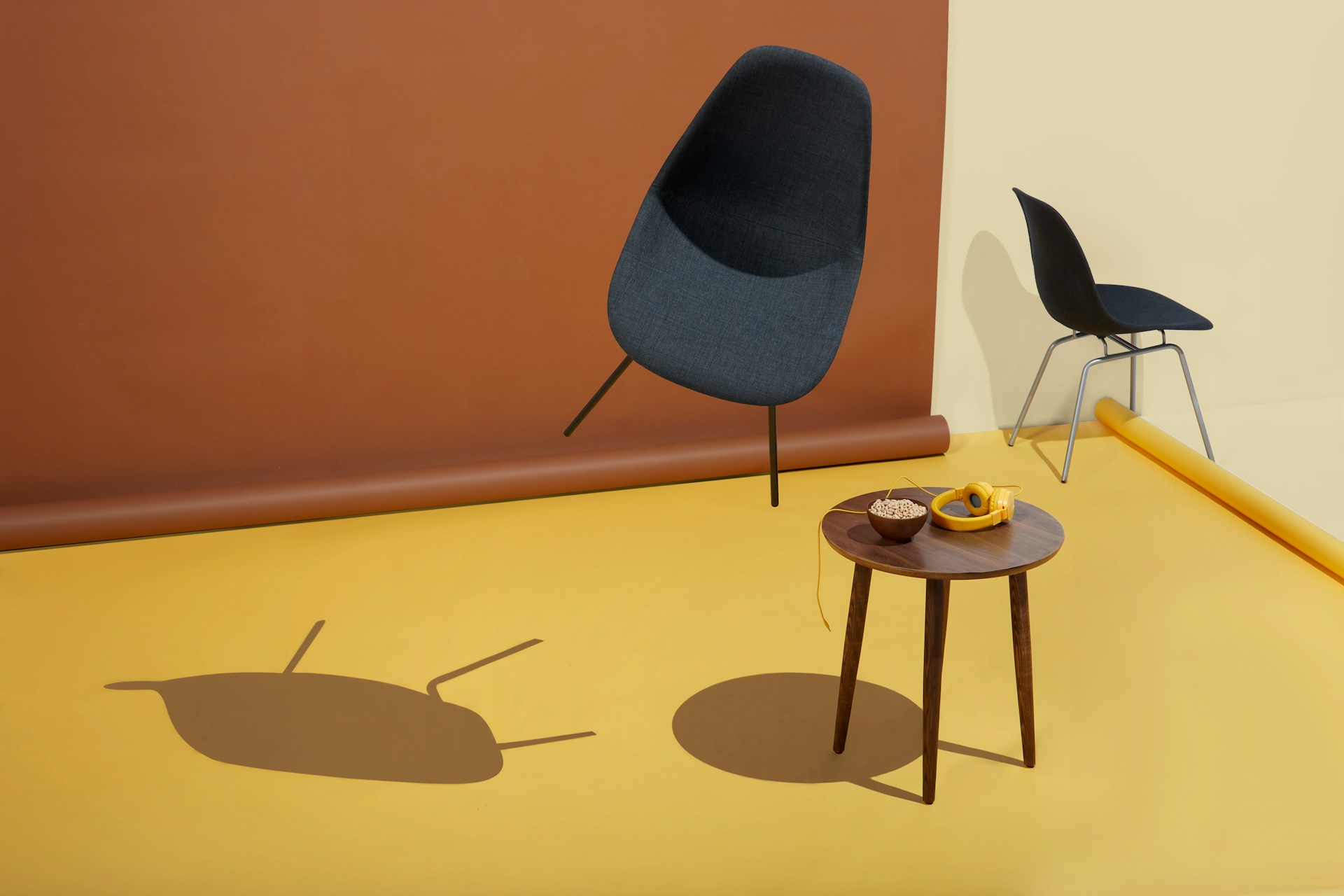 Modern chairs and table on a yellow floor with a brown backdrop, creating soft shadows. | Photo by Inside Weather on Unsplash