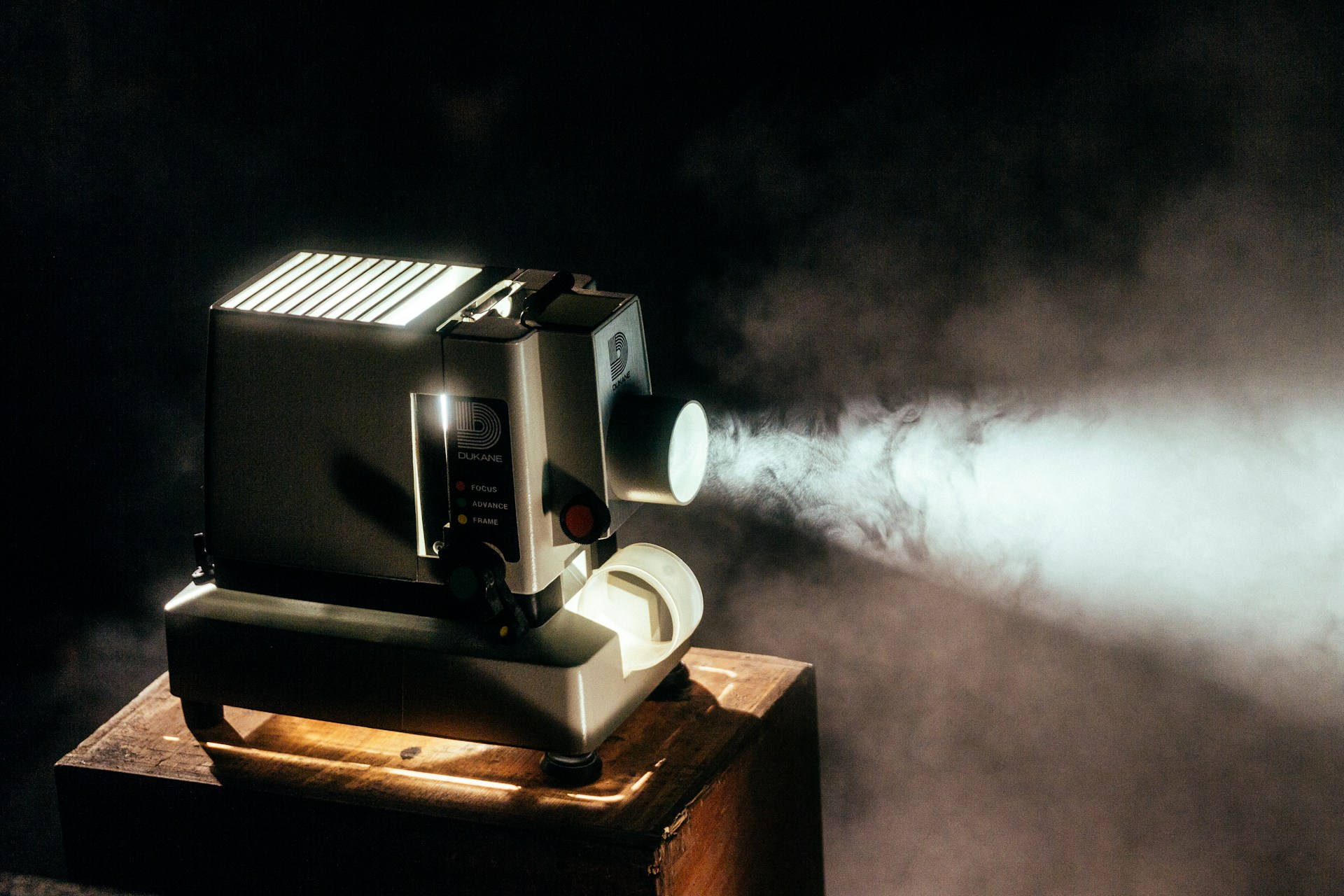 Vintage projector emitting light beam in a dark room with visible smoke. | Photo by Jeremy Yap on Unsplash