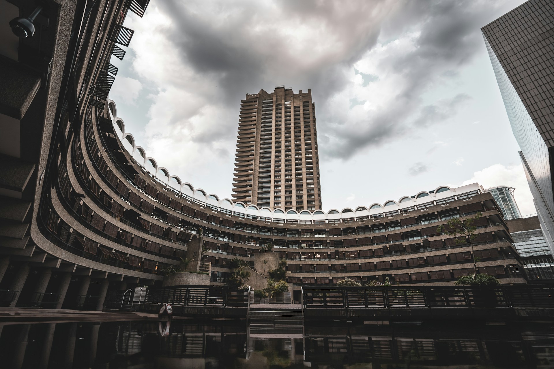 Curved Brutalist architecture with a tower in the background under a cloudy sky. | Photo by Artem Zhukov on Unsplash