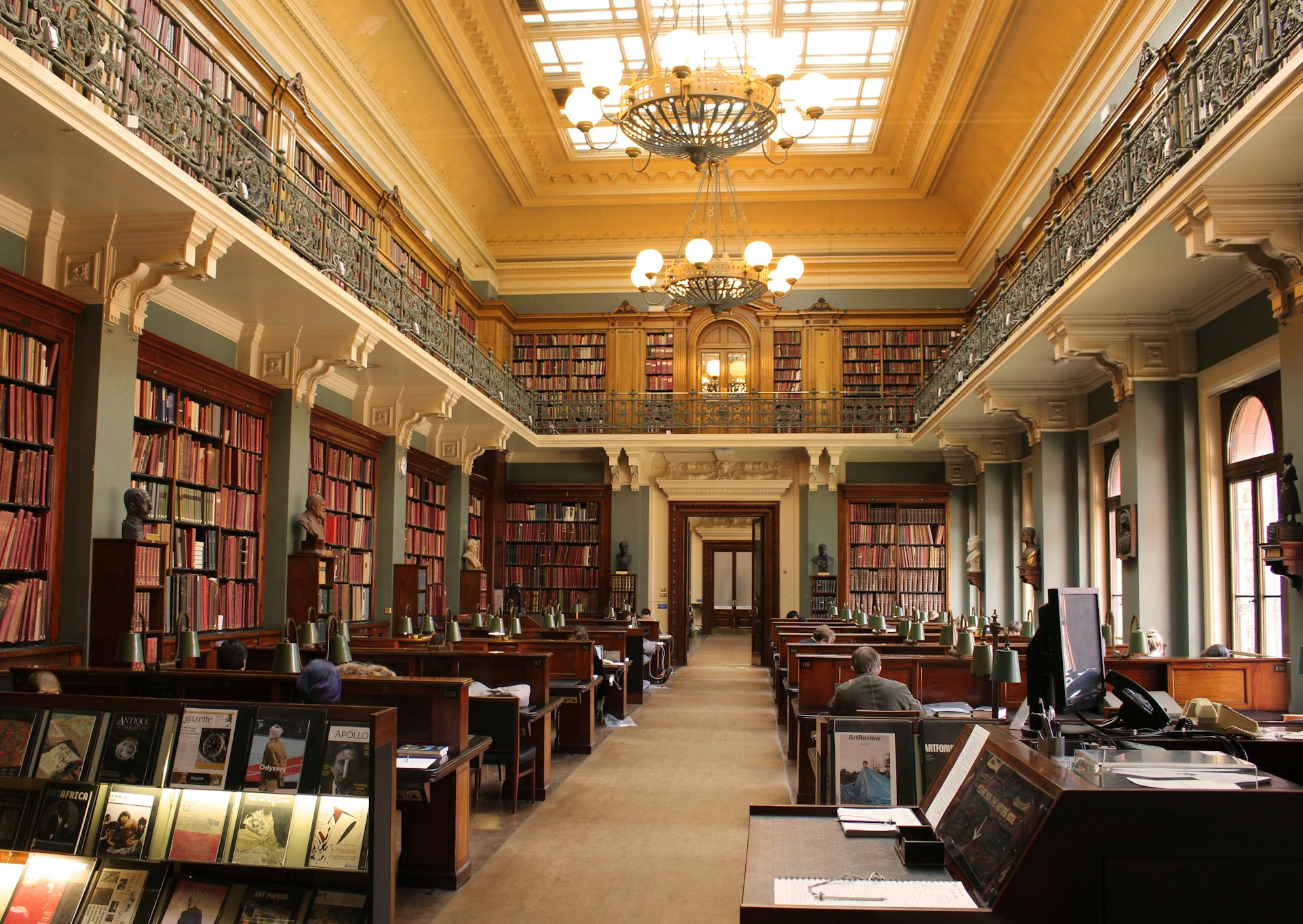Elegant library interior with bookshelves, desks, chandeliers, and a balcony. | Photo by Sebastien LE DEROUT on Unsplash