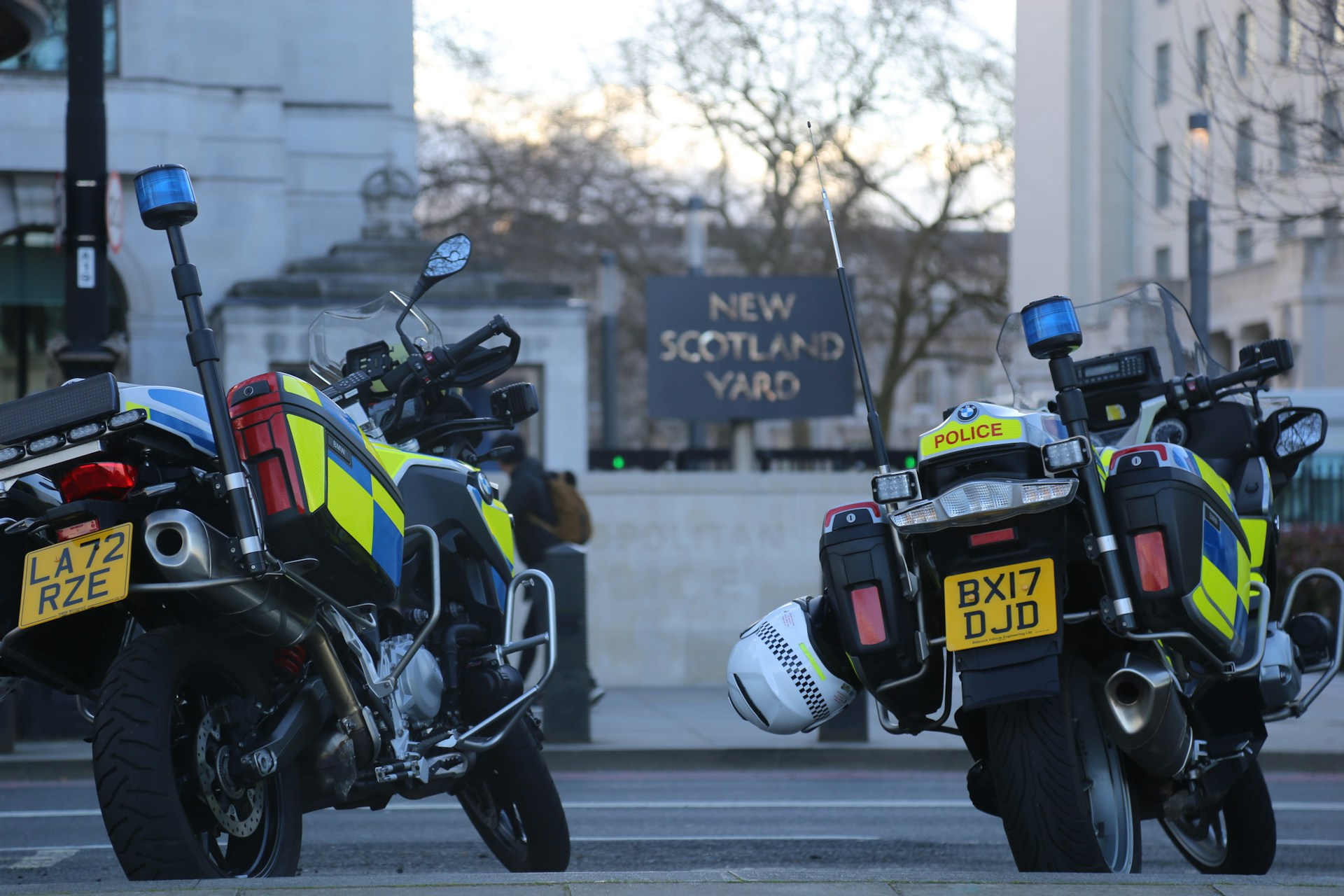 Two parked police motorcycles in front of the New Scotland Yard sign. | Photo by Kelsey Farish on Unsplash