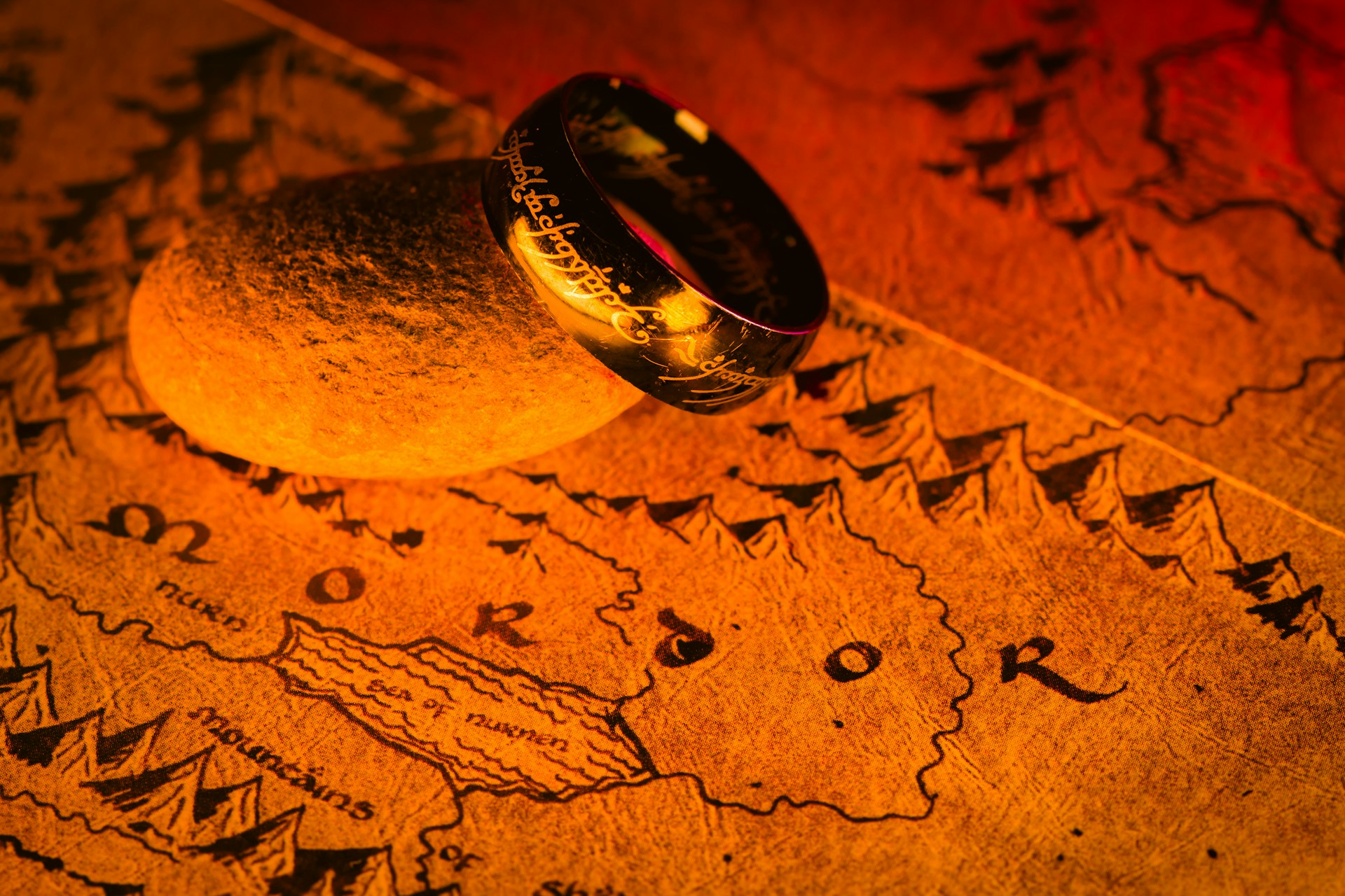 A ring with inscriptions rests on a map marked "Mordor" in a warm, glowing light. | Photo by D A V I D S O N L U N A on Unsplash