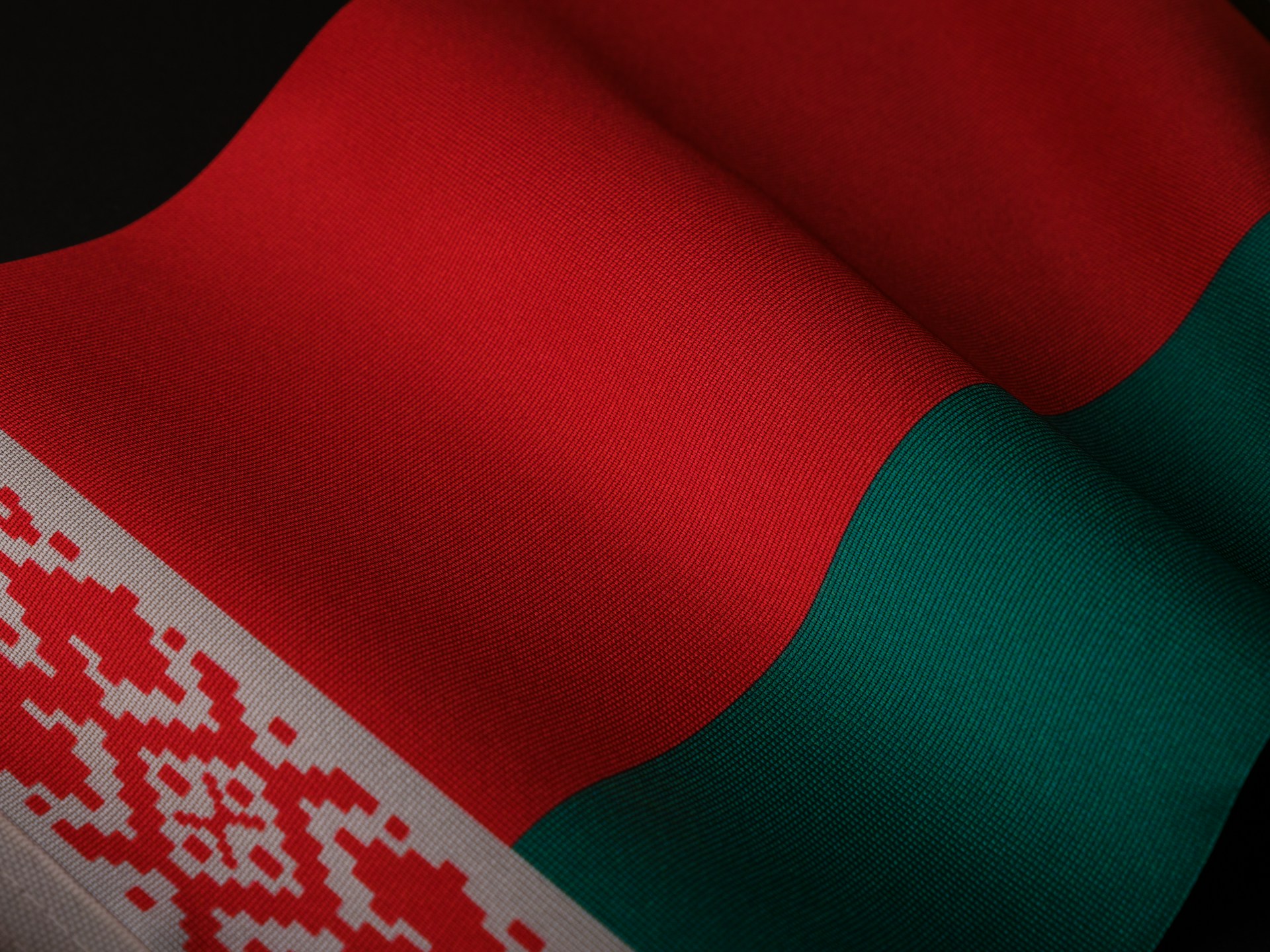 Close-up of a wavy Belarusian flag with red, green, and a decorative white-and-red pattern. | Photo by engin akyurt on Unsplash