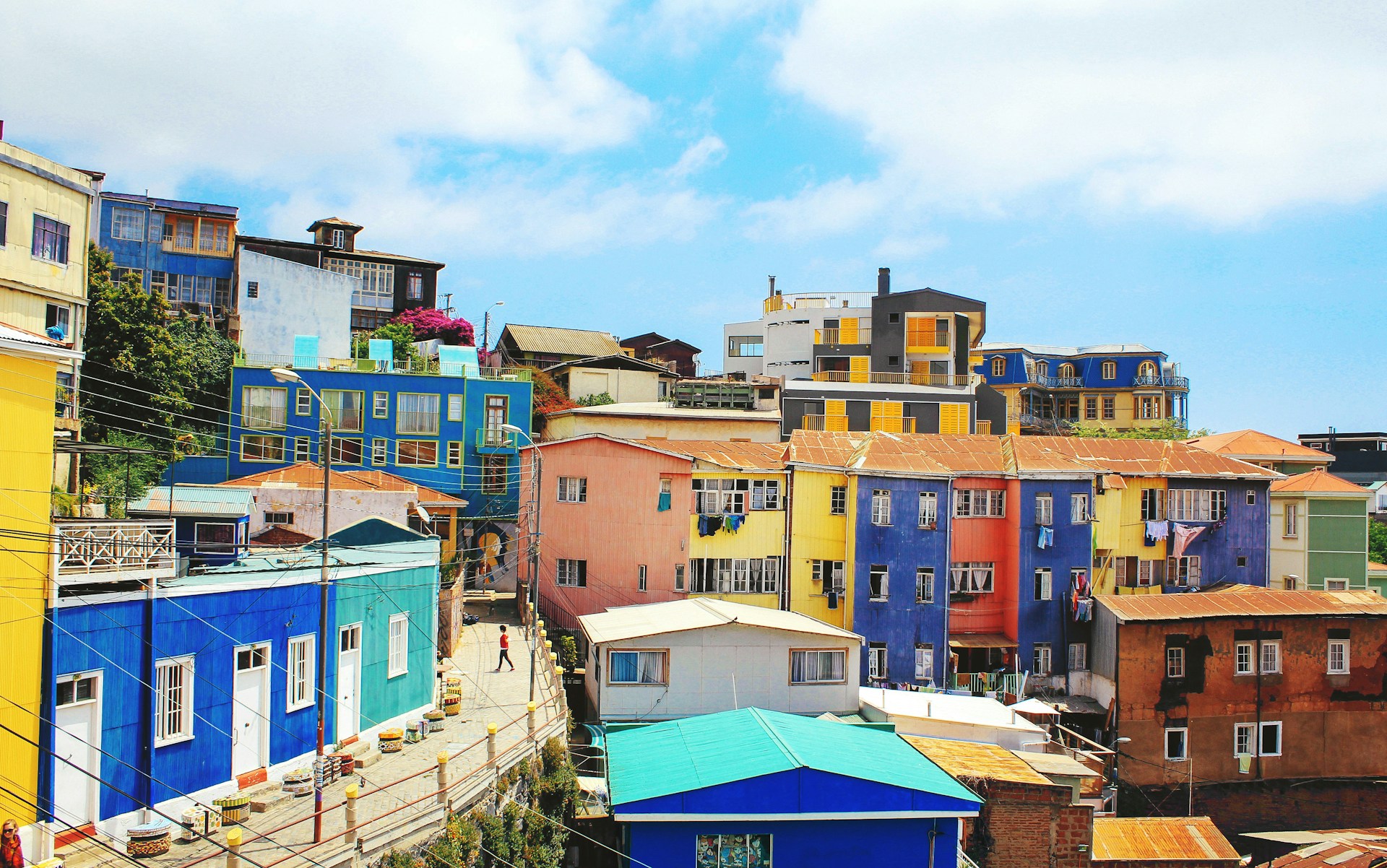 Colorful hillside buildings under a blue sky. | Photo by Loïc Mermilliod on Unsplash