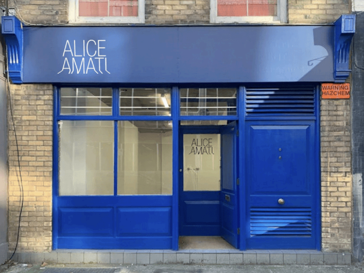 Blue storefront with signage "ALICE AMATI" above the door and reflective windows. | Alice Amati