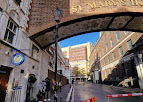 Narrow street under an archway with "St Mary's Hospital" sign, leading to modern buildings under a clear sky. | Alexander Fleming Laboratory Museum