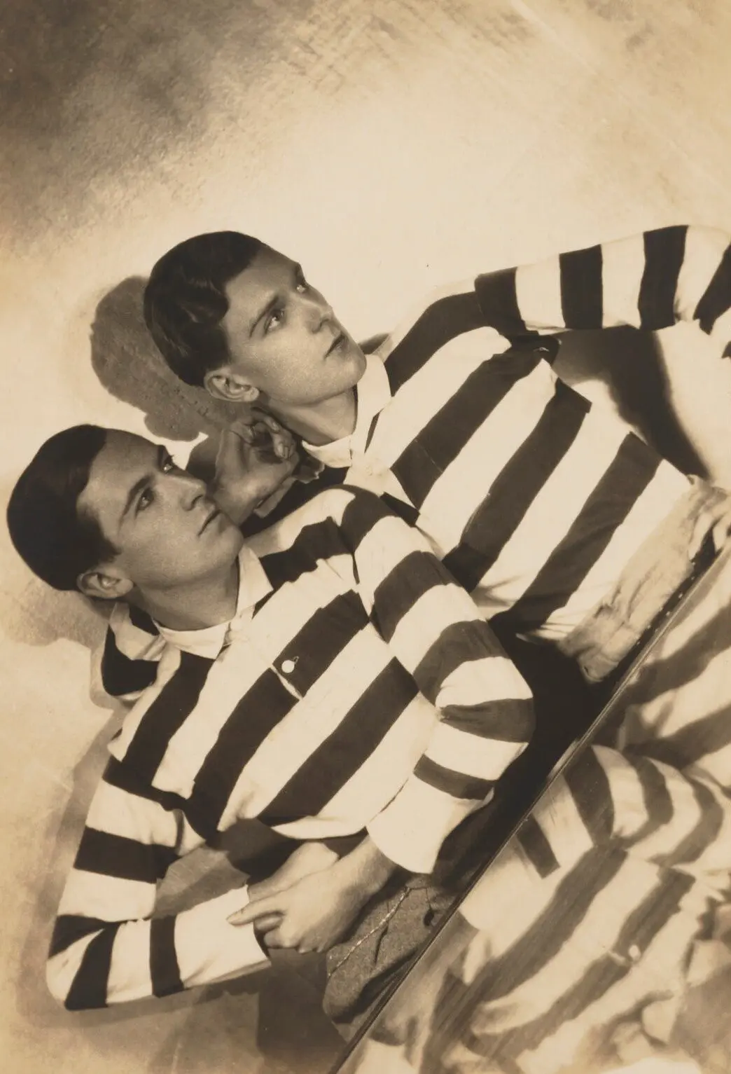 Two people in striped shirts lying on the floor, vintage photo style.