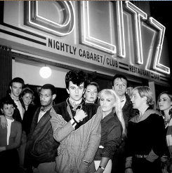 People standing in front of a cabaret club called "BLITZ" at night.