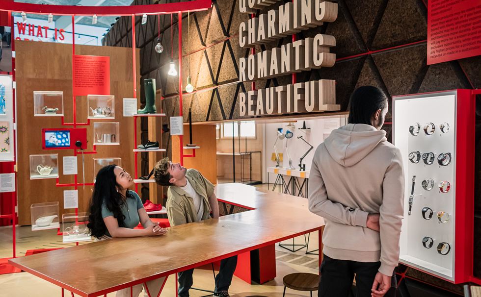 A modern exhibition space with bold signage featuring words like "Charming" and "Beautiful," showcasing colorful shoes and watches.