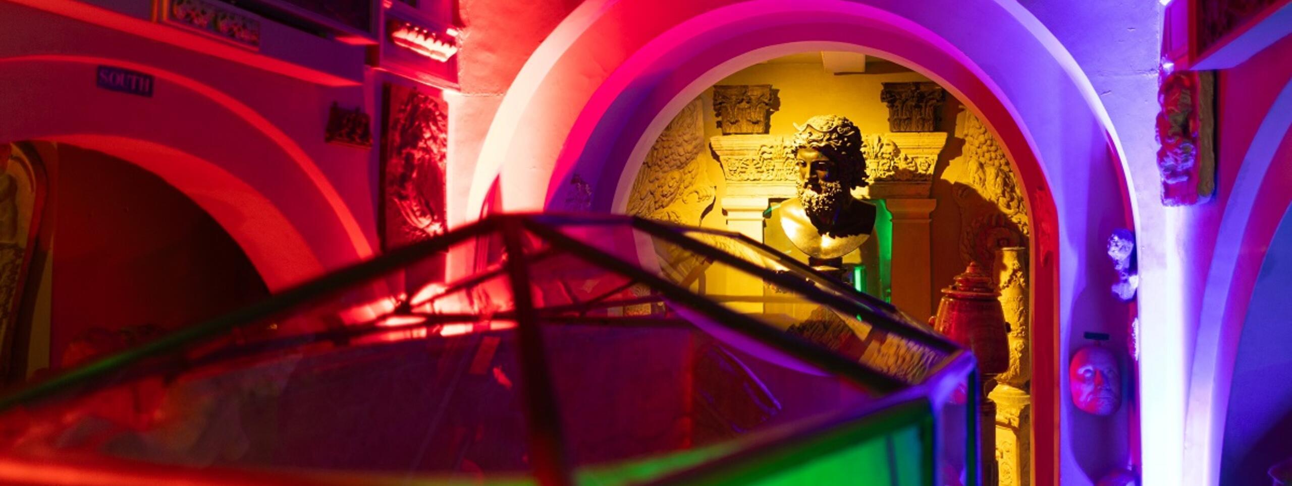 A vibrant, illuminated interior featuring colorful lighting on arches and decorative elements, creating a lively atmosphere.