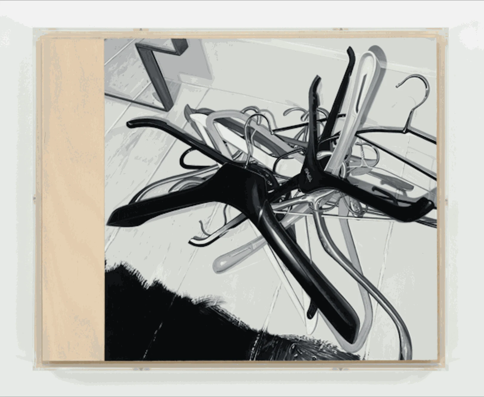 A chaotic arrangement of black and silver clothing hangers tangled on a light colored surface, with a minimalist background.