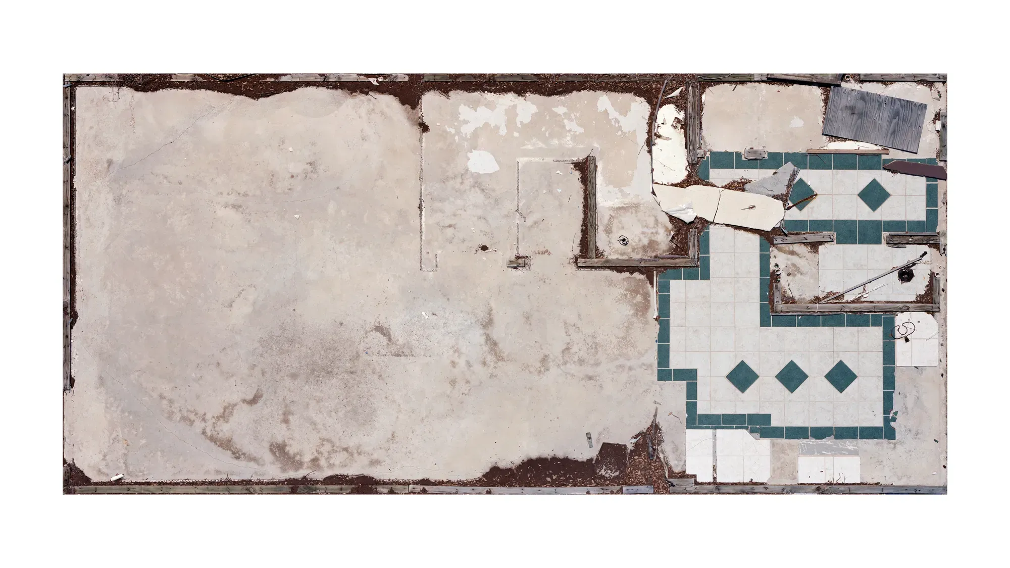 An overhead view of a dilapidated floor, featuring cracked concrete and broken tiles arranged in a diamond pattern.
