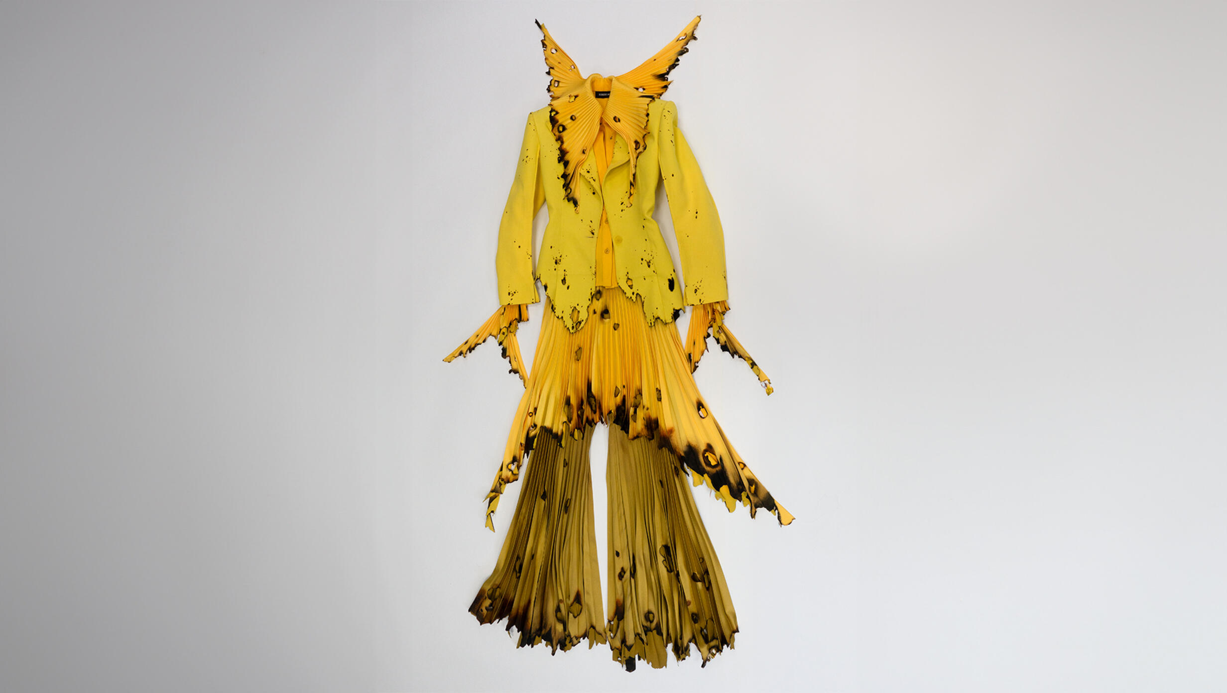 A vibrant yellow dress adorned with striking black and yellow feathers, showcasing a bold and unique design.