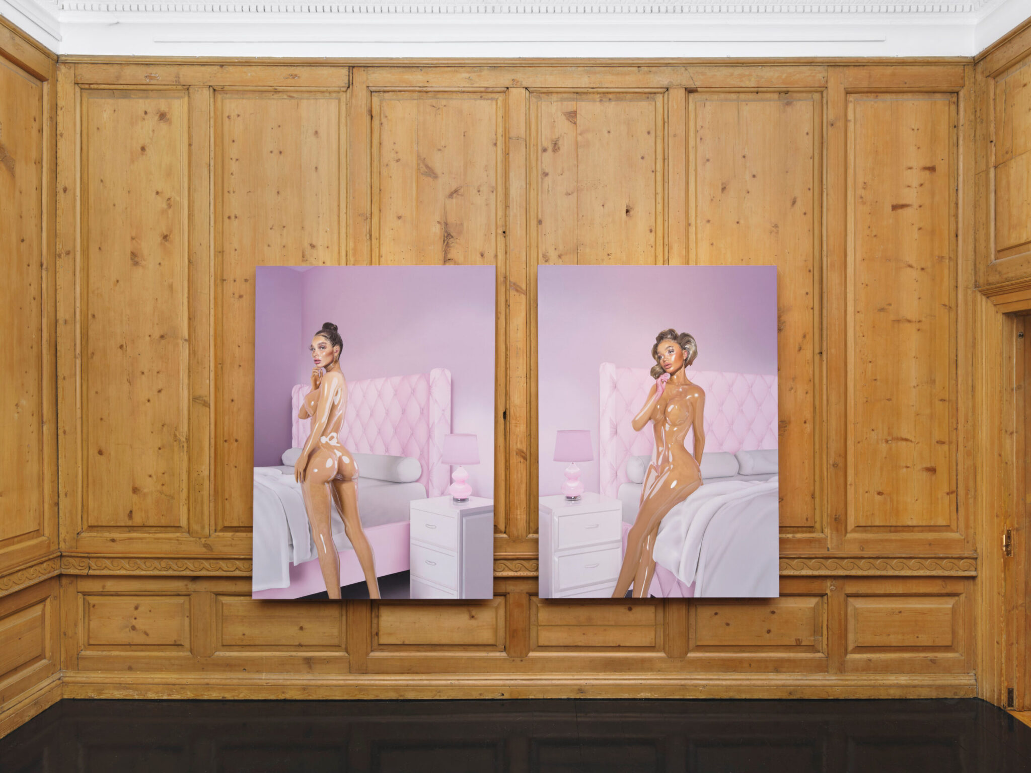Two framed artworks, each depicting a nude woman in a pastel pink bedroom setting, hung on a light brown paneled wall.
