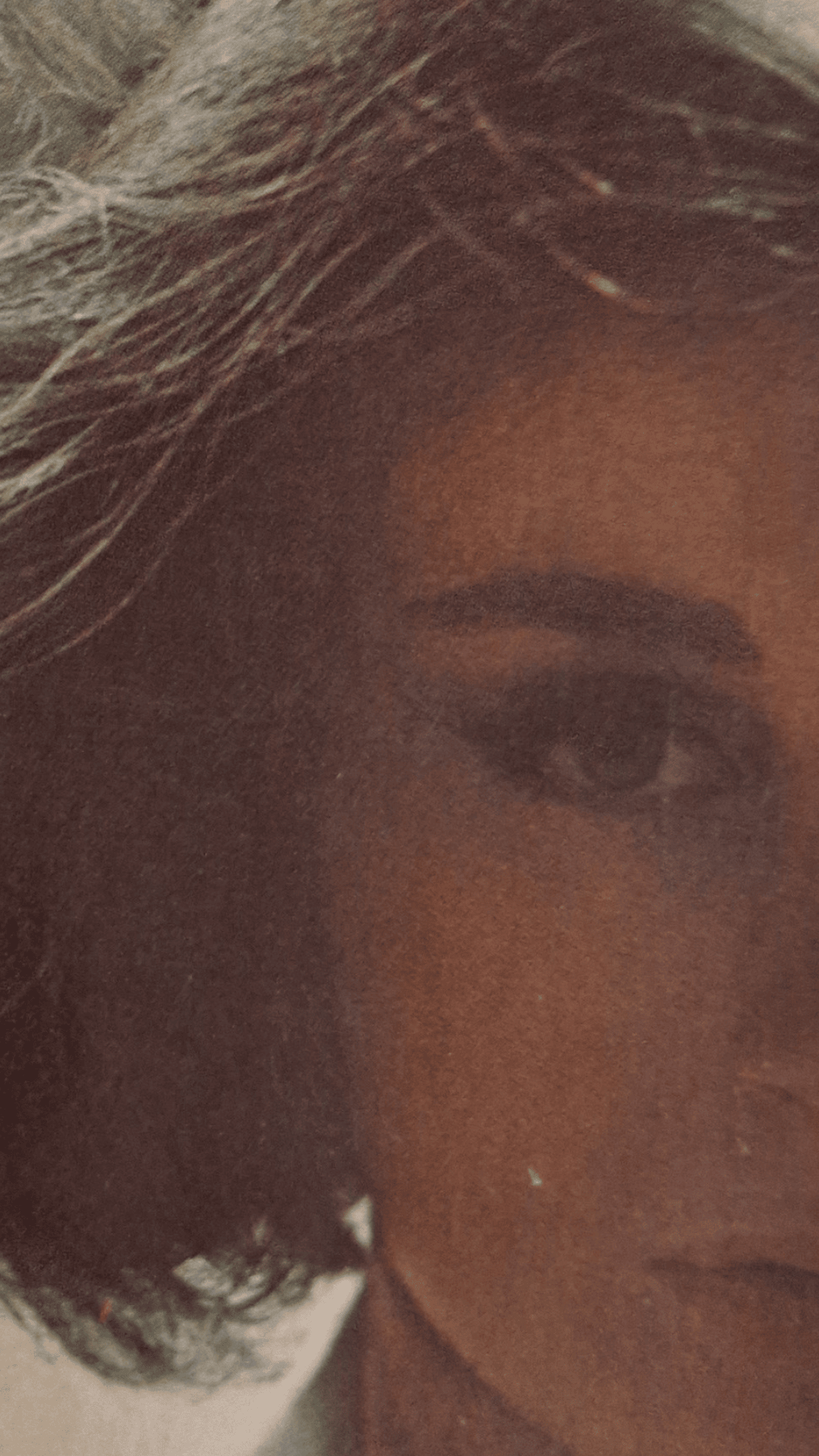 Close-up of a woman's face, showing a portion of her dark hair, eye, and forehead. | 2024 Vagina Museum