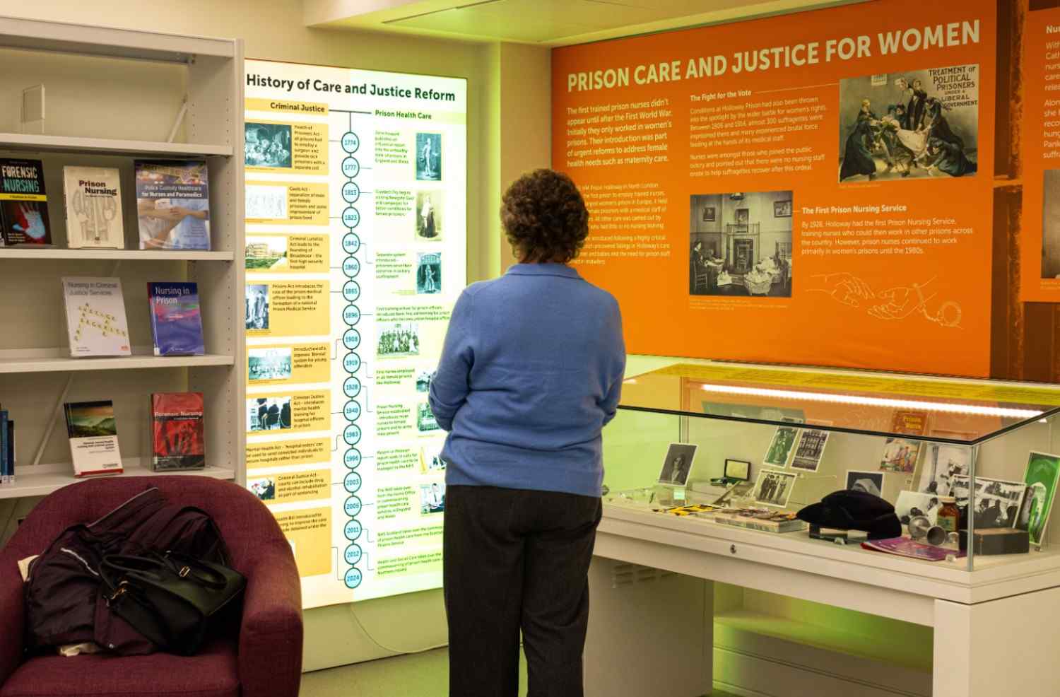 A woman standing in front of a wall and display cabient, with the text title "Prison care and justice for women"