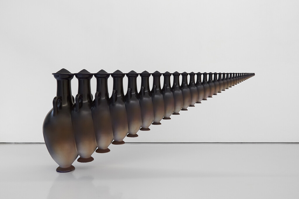 A row of elegantly shaped, dark ceramic vases stretches towards the horizon against a minimalist white background.