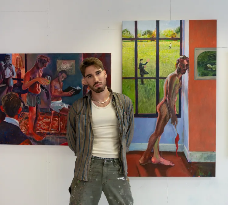 A person stands in an art studio surrounded by vibrant paintings, including a nude figure and a scenic landscape through a window.
