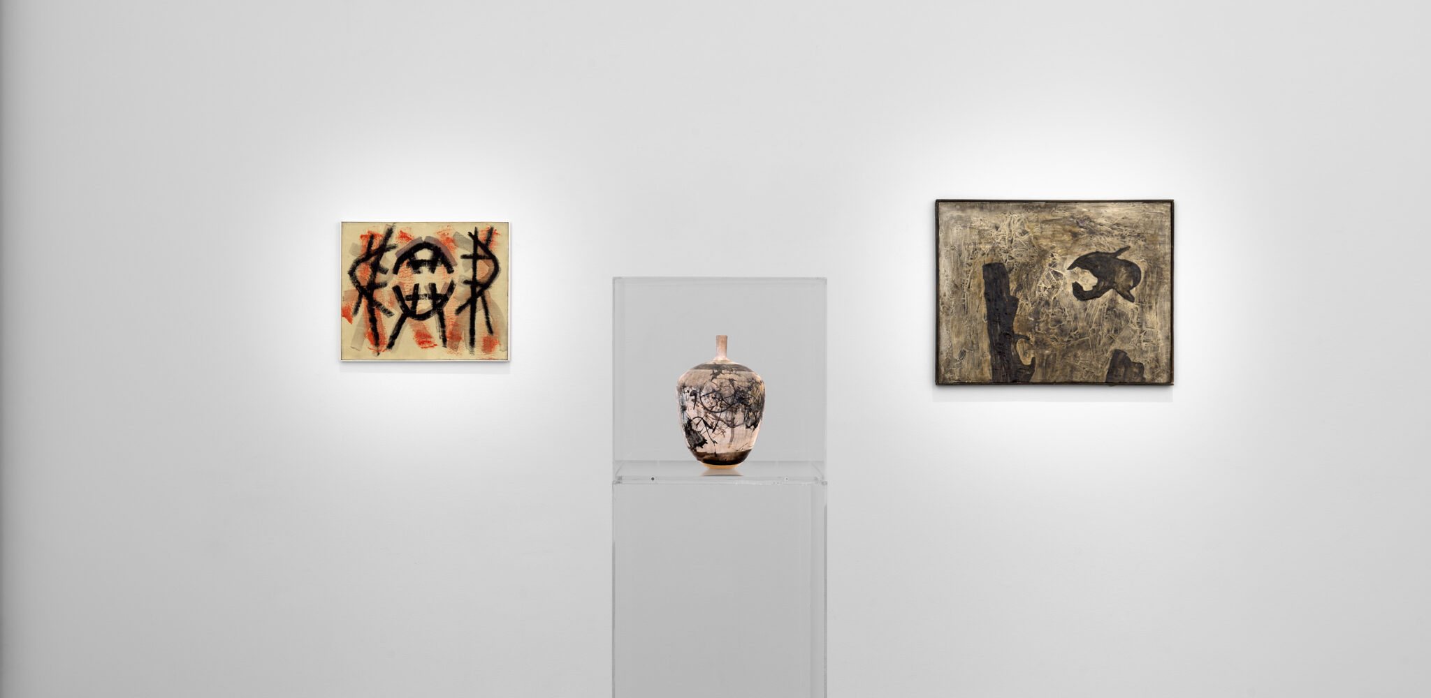 A collection of art pieces displayed in various picture frames on a wall inside an art gallery.