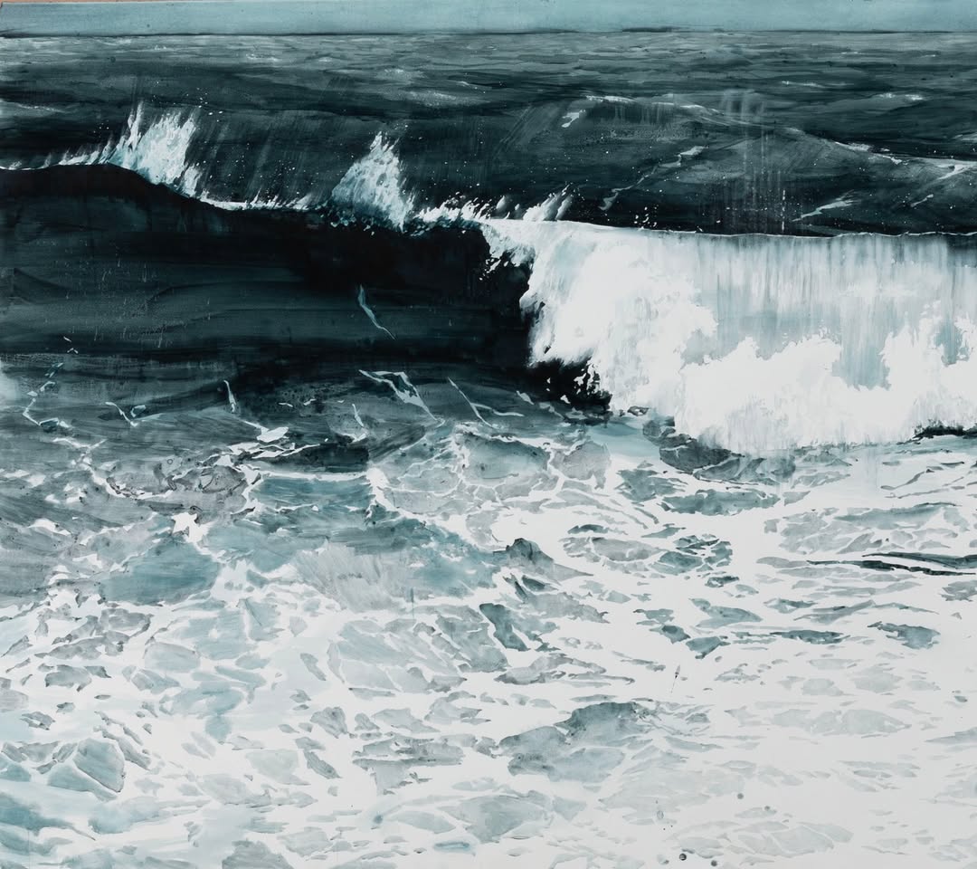 A dramatic seascape featuring dark waves cresting with white foam, showcasing a powerful ocean contrast in hues of blue and gray.