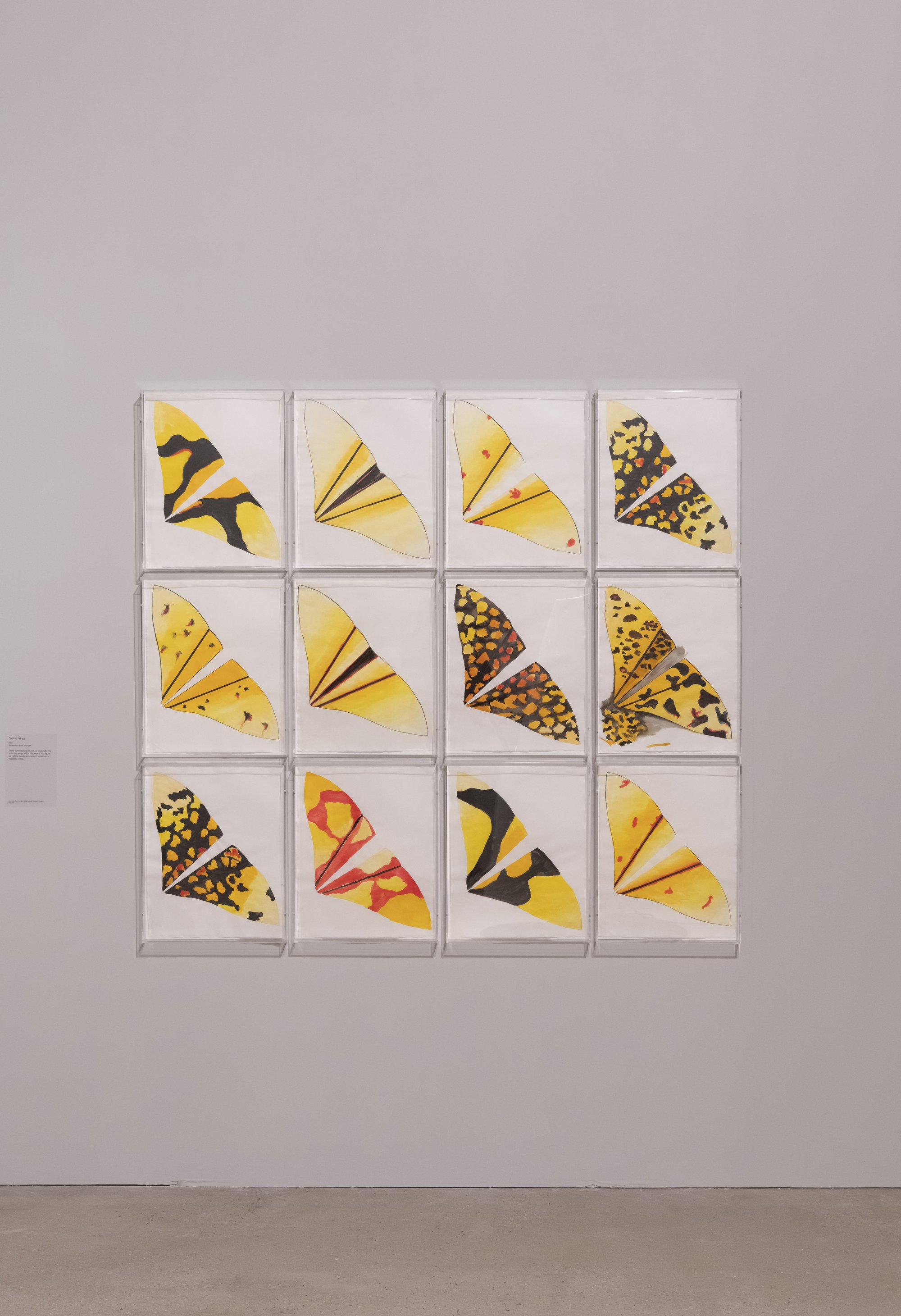 A wall covered with numerous pieces of paper featuring various drawings and paintings, creating a colorful and eclectic art display in an indoor gallery setting.