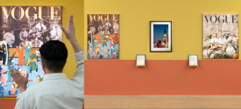 A woman with her hands raised in a room filled with art, surrounded by paintings and picture frames.