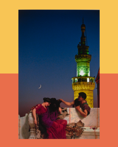 A group of people sitting on a ledge with a tower in the background under a clear sky. They are wearing various types of clothing, and there is a wall near them.