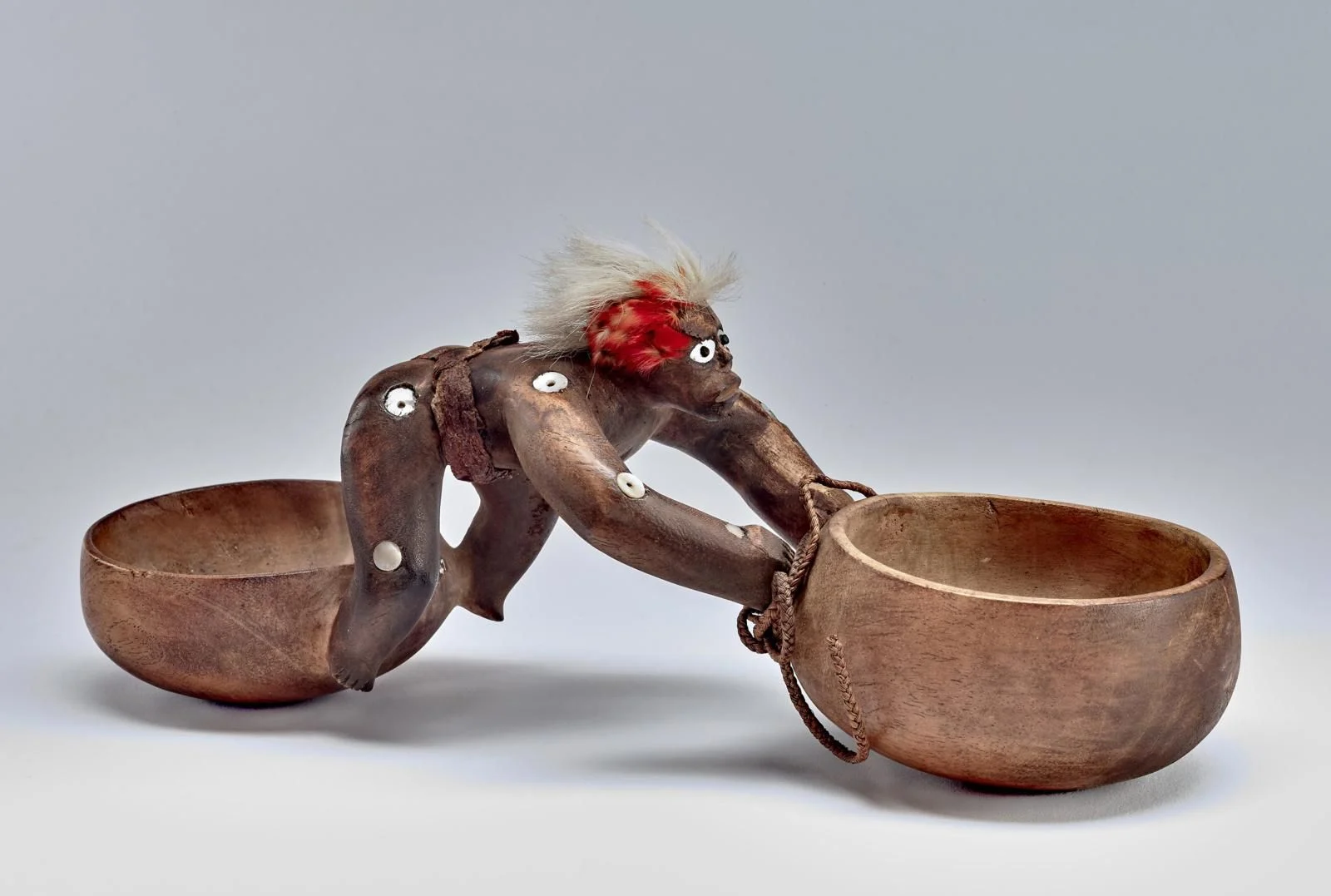 A wooden bowl is being held by a person, set against an indoor backdrop, with a focus on the fashion accessory of their sandals in the foreground.