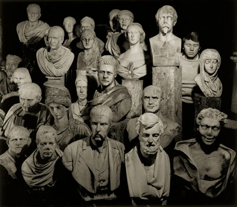 A group of statues depicting people, including a boy and a man, all smiling and posing together indoors. The statues feature human faces and are dressed in clothing.