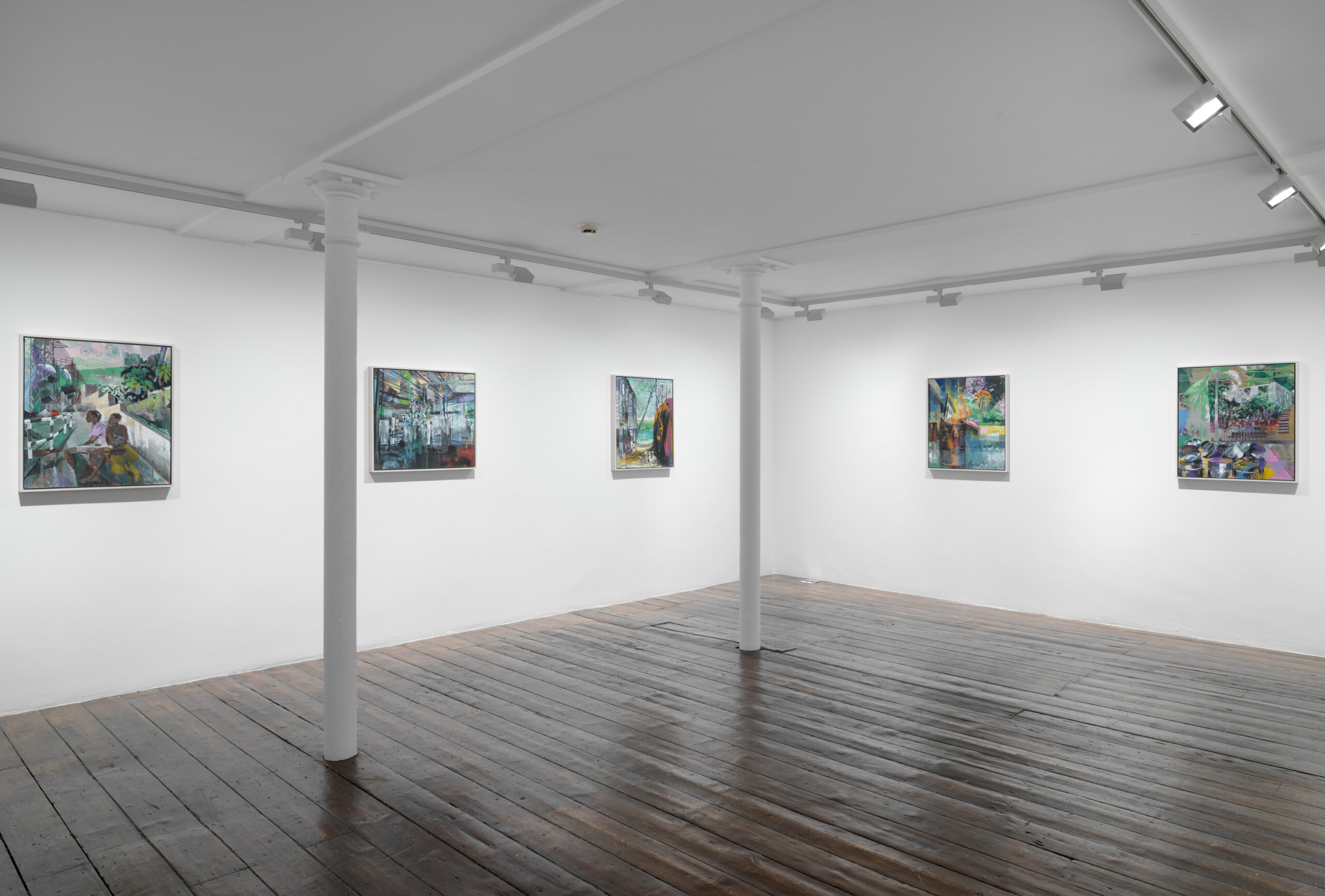 A spacious indoor art gallery featuring white walls adorned with various paintings in picture frames. The ceiling is visible above, and the floor is unobstructed, creating a bright and inviting atmosphere for viewers to explore the artwork.