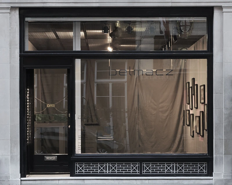 Storefront with a curtain hanging in the window, showcasing a rectangular building outdoors. | 2026 Belmacz