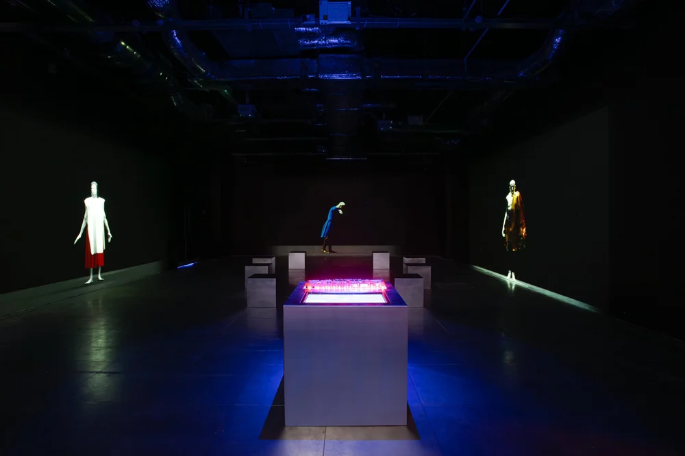 A room featuring a black floor and a black wall illuminated by a light.