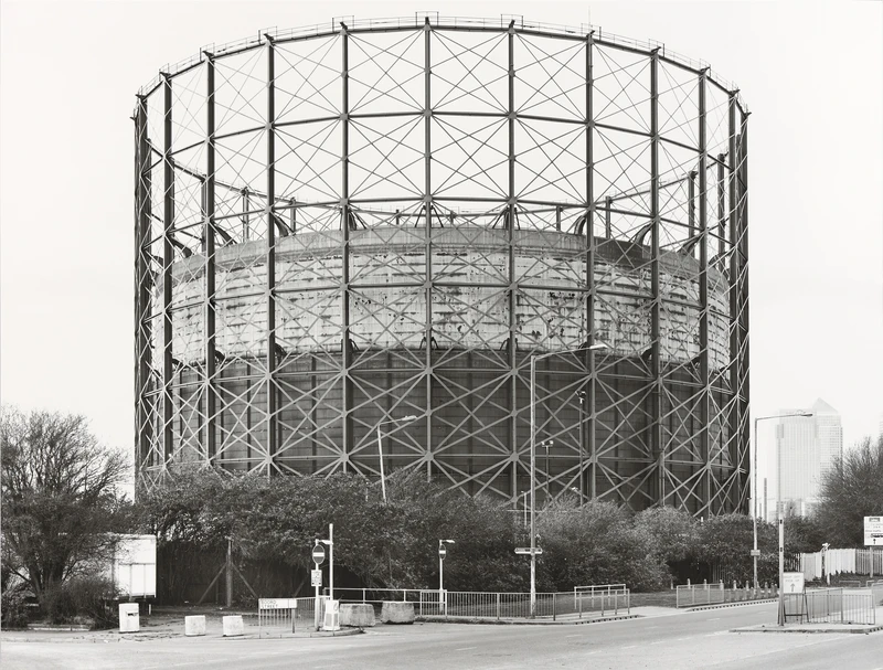 A large metal dome structure surrounded by trees, set against a cloudy sky in black and white.