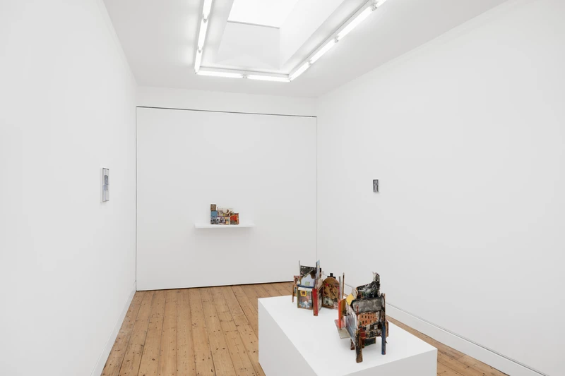 A room featuring a white wall and a white table adorned with various objects.