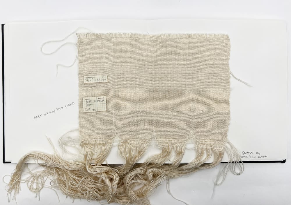 A piece of fabric with threads laid on top, capturing a textured and intricate design.