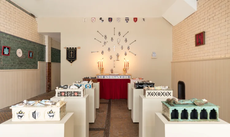 A room featuring white tables adorned with red tablecloths, surrounded by chairs. The space includes a vase and is designed for dining, with visible wall elements and a ceiling above.