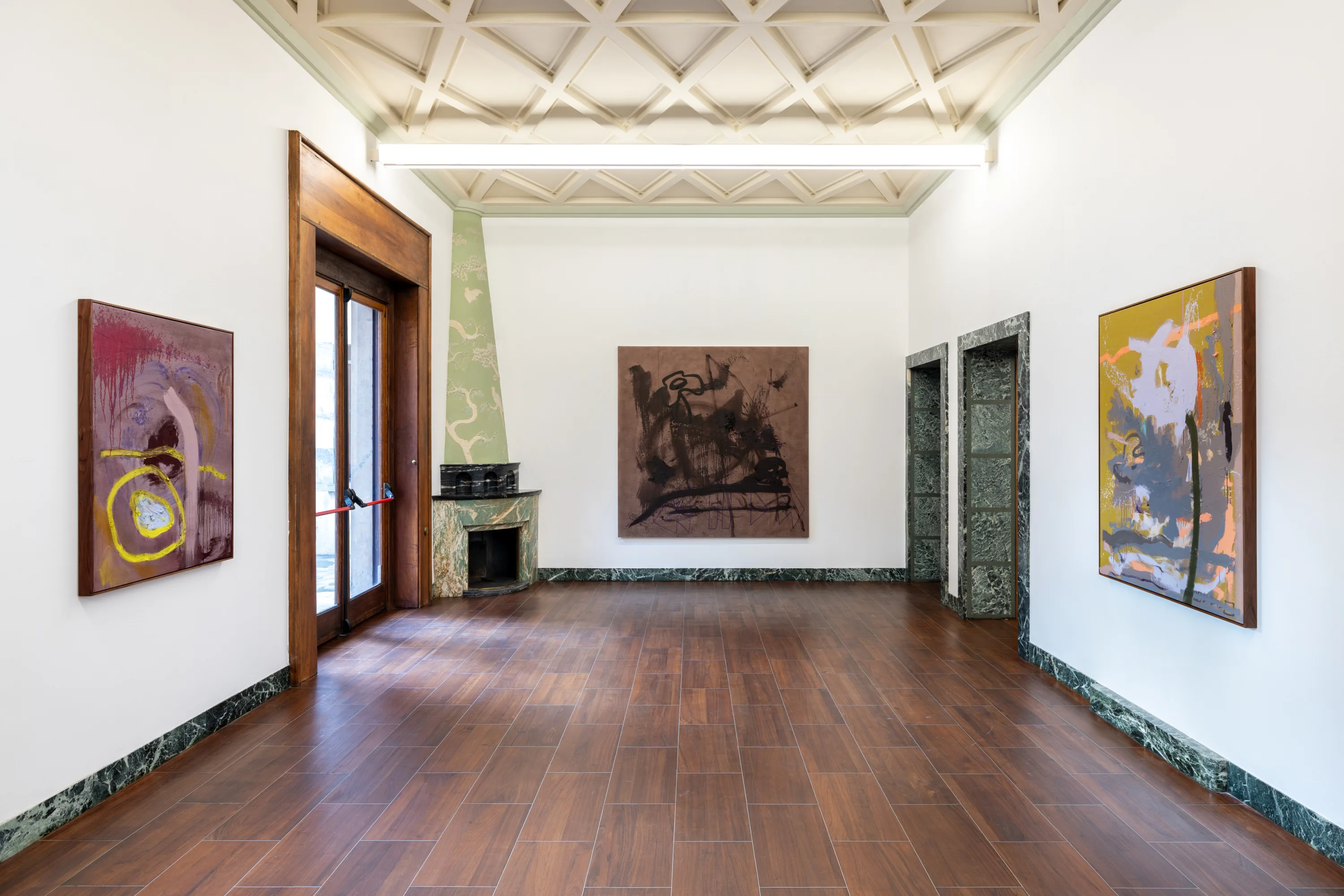 A room featuring an art gallery setup with various pieces of art displayed on the walls, framed pictures, a polished floor, and a well-lit interior design.