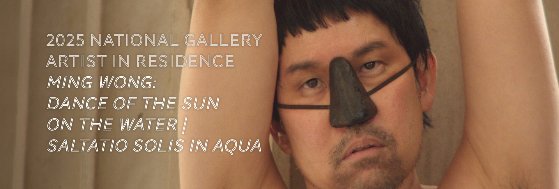 A man with a unique artistic depiction of a nose on his face, showcased in an indoor setting related to the 2025 National Gallery Artist in Residence program featuring Ming Wong's work titled "Dance of the Sun on the Water Saltatio Solis in Aqua."