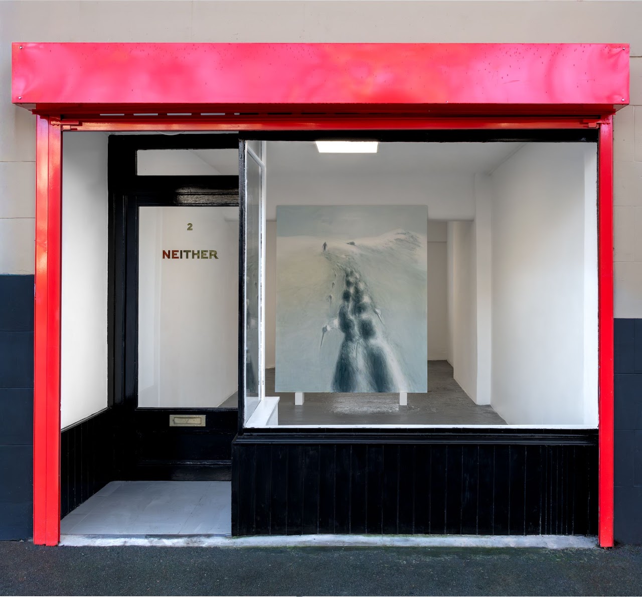 A storefront featuring red and black colors, with a painting displayed in the window.