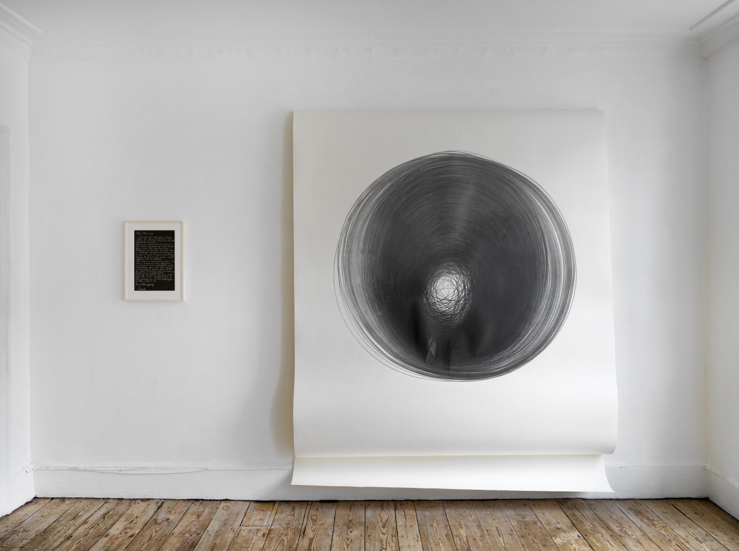 A large black circle on a white wall in an indoor setting, with a clothes dryer and washer visible on the floor.