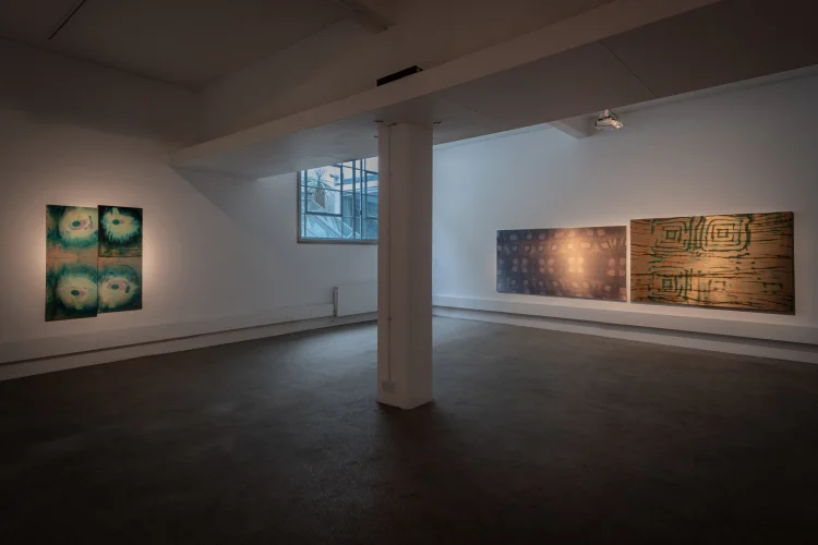 A room featuring various paintings displayed on the walls, showcasing an art gallery atmosphere with a focus on visual arts.