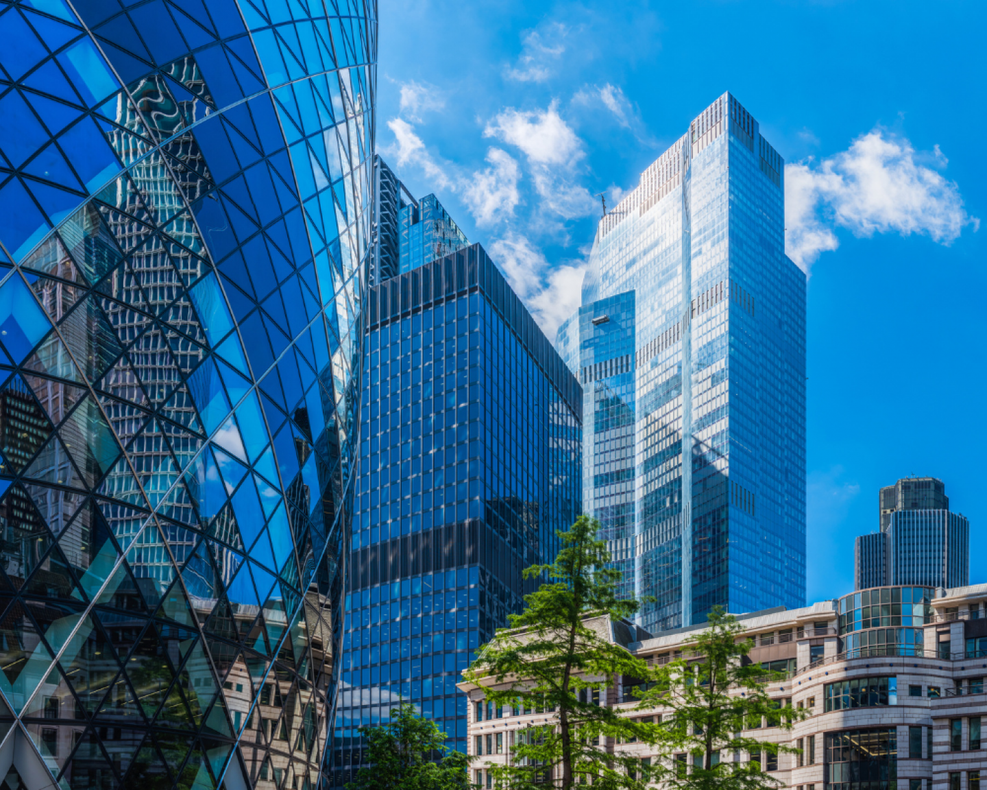 A cityscape featuring modern skyscrapers with reflective glass facades under a blue sky with clouds.