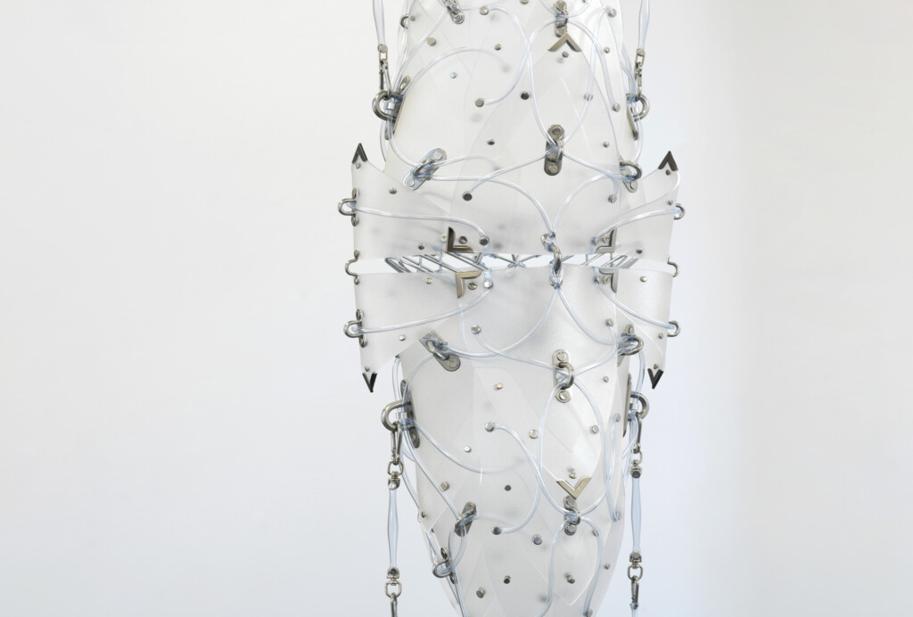 A clear, abstract sculpture featuring a combination of transparent and reflective materials, with intricate designs and metallic elements.