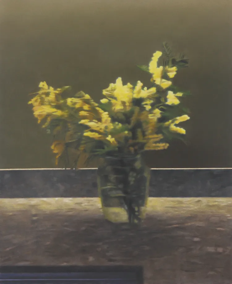 A bouquet of yellow flowers in a glass vase against a muted background.