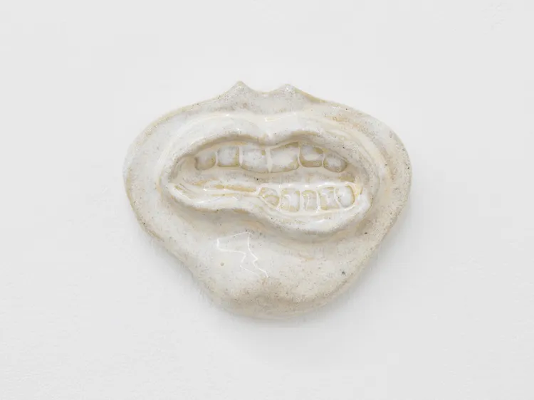 A ceramic piece resembling a mouth with visible teeth, displayed on a white background.