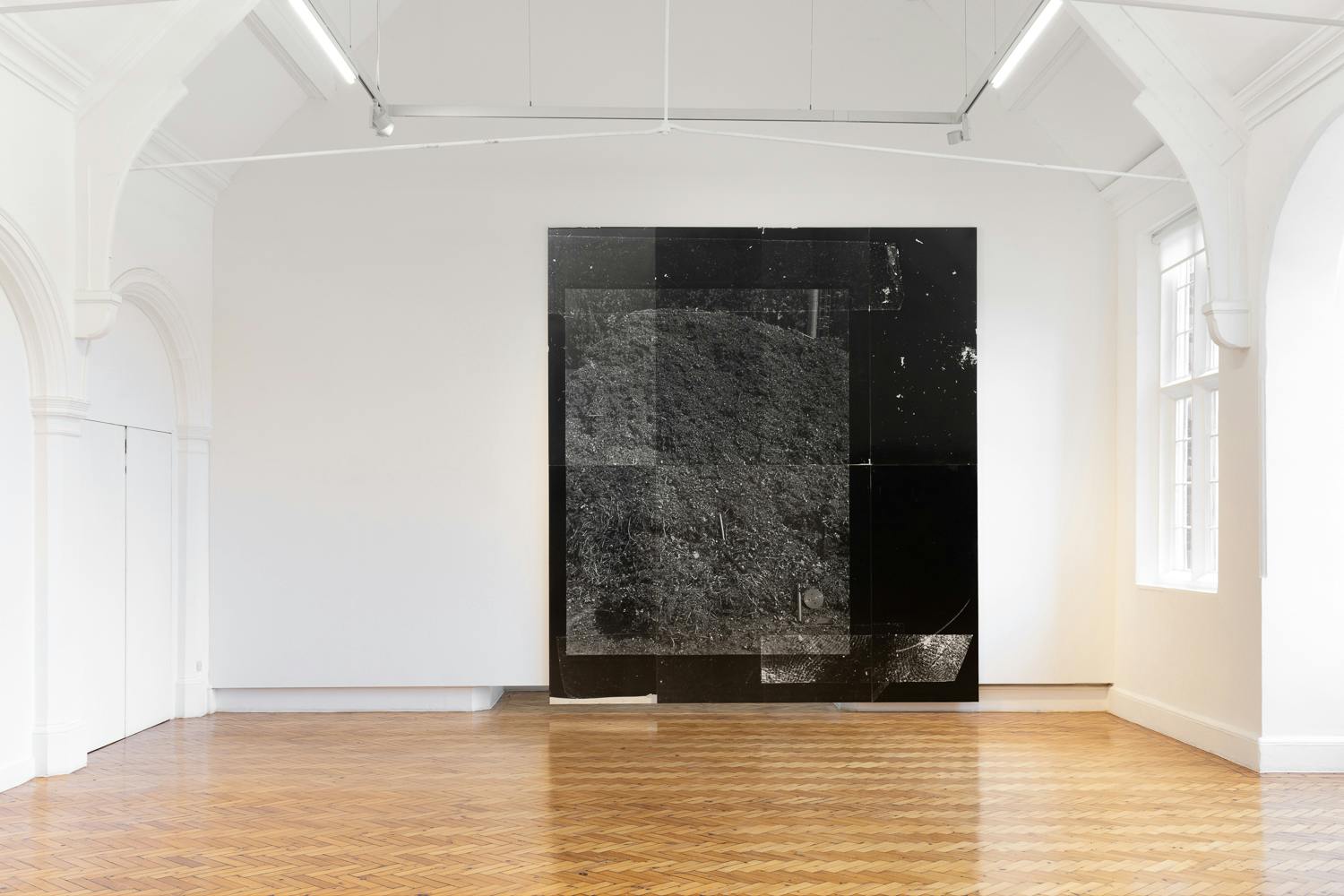 A large black and white abstract artwork displayed in a bright, minimalist gallery space with wooden flooring.
